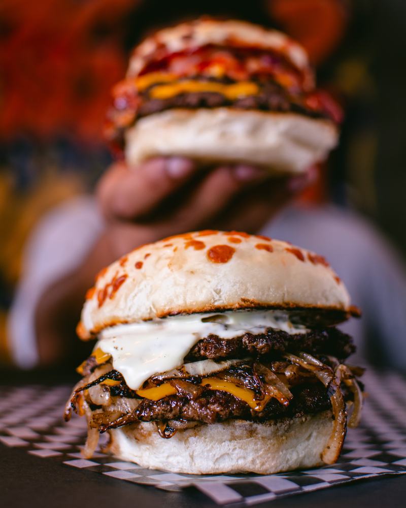 Hamburguesa doble con cebolla caramelizada y salsa blanca sobre papel a cuadros, producto de Burger Cheep