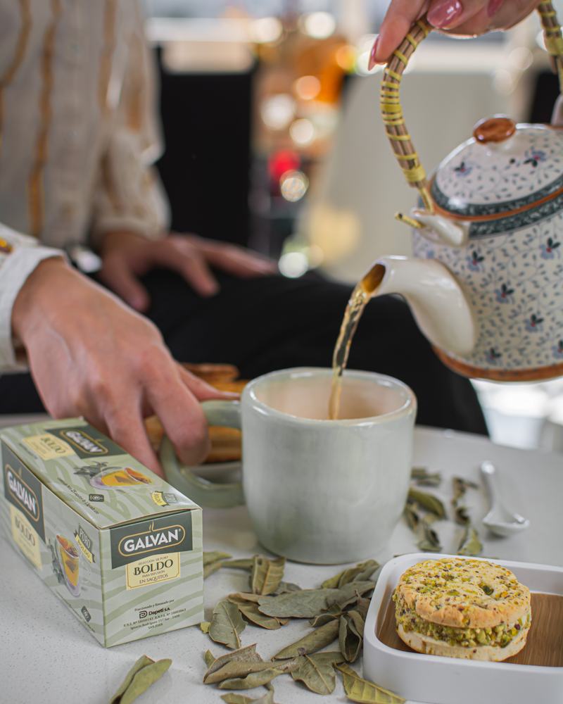 Té de boldo Galvan en saquitos, junto a una taza, una tetera y hojas de boldo, producto de Galvan