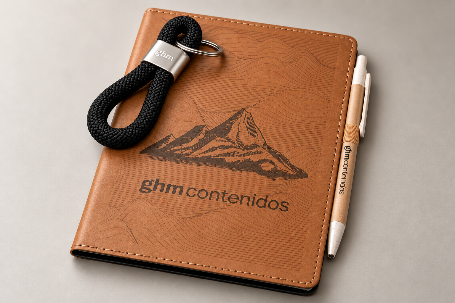 Regalo institucional para GHM Contenidos: libreta de cuero grabada con cordillera, llavero de cuerda y bolígrafos ecológicos, por TramaHub